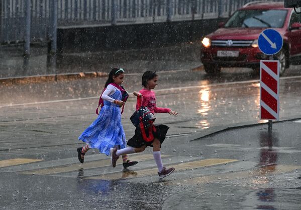 Девочки перебегают через дорогу во время сильного дождя в Москве - Sputnik Абхазия