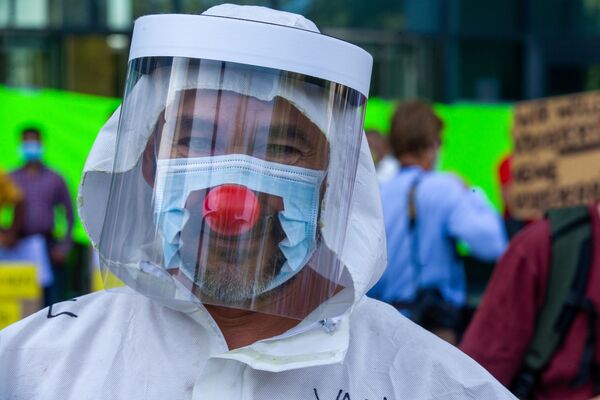 Мужчина в маске и с клоунским носом во время протестов в Брюсселе - Sputnik Абхазия