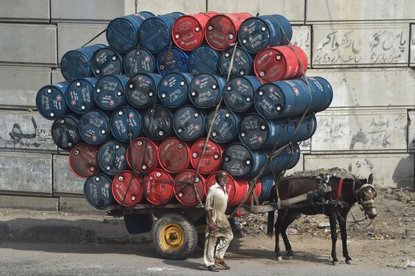 Мужчина рядом с повозкой груженной бочками с нефтью на улице в Лахоре, Пакистан - Sputnik Абхазия