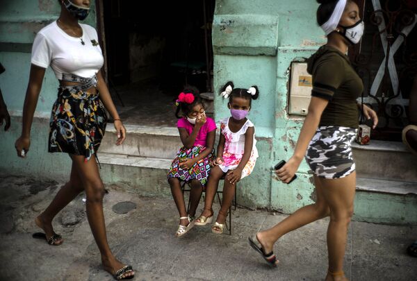 Девочки в масках ждут своих родителей, сидя на стуле в Гаване, Куба - Sputnik Абхазия