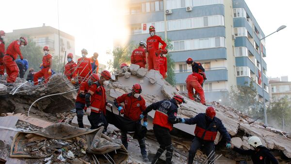 Рабочие несут тело пострадавшего во время проведения спасательных операций на месте землетрясения в Эгейском море, в прибрежной провинции Измир, Турция,  - Sputnik Абхазия