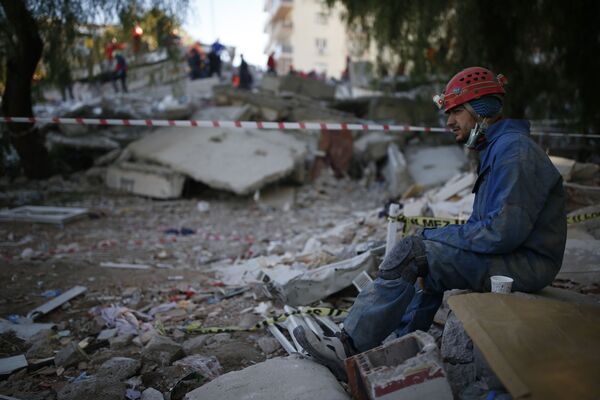 Спасатель во время отдыха на месте разрушенного здания после землетрясения в Измире  - Sputnik Абхазия