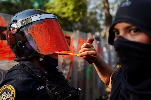 Девушка красит шлем сотрудника полиции во время акции протеста против гендерного и полицейского насилия в Мехико - Sputnik Абхазия
