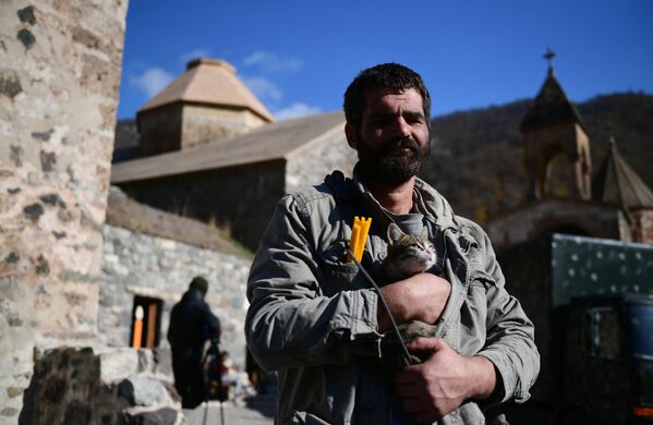 Мужчина держит на руках кота возле храма в монастыре Дадиванк в Нагорном Карабахе - Sputnik Абхазия