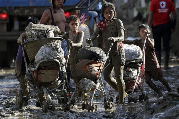 Дети везут коляски с вещами в деревне, пострадавшей от тайфуна Vamco на Филиппинах - Sputnik Абхазия