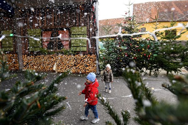 Дети играют с искусственными снежинками на рождественской ярмарке в Германии - Sputnik Абхазия
