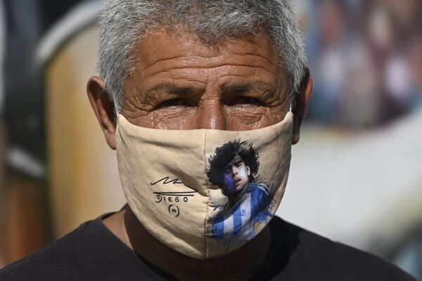 Мужчина в маске с изображением Диего Марадоны в Аргентине  - Sputnik Абхазия