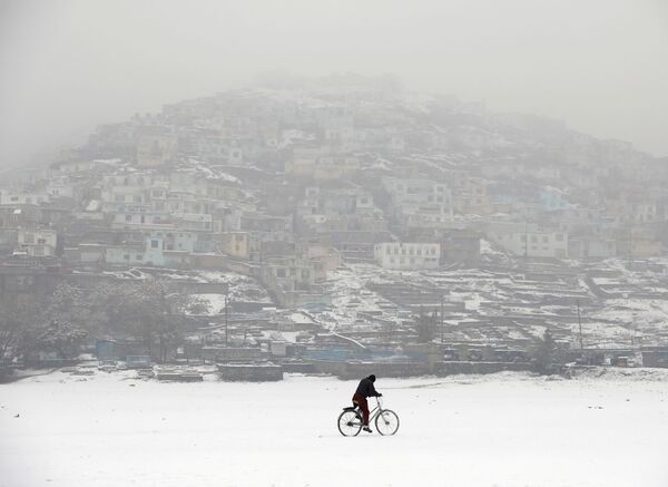 Велосипедист во время снегопада на фоне заснеженного Кабула, Афганистан - Sputnik Абхазия