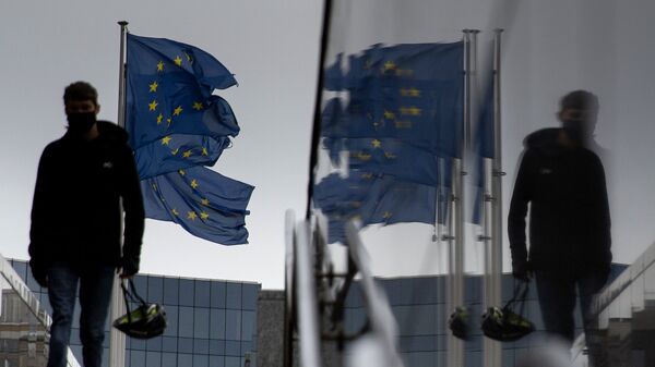 Мужчина идет мимо флагов ЕС у штаб-квартиры ЕС в Брюсселе - Sputnik Абхазия