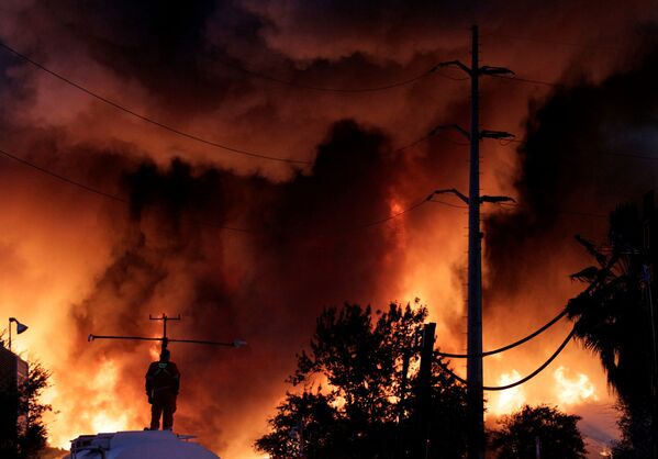 Пожарный стоит на резервуаре с водой во время пожара на заводе по переработке металлолома компании Deacero в Гуадалупе, на окраине Монтеррея, Мексика - Sputnik Абхазия