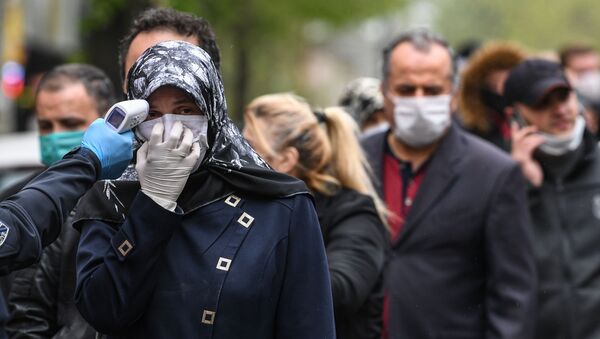 Офицер муниципалитета проверяет температуру людей, пока они ждут входа на рынок симпозиумов в Газиосманпаша в Стамбуле - Sputnik Абхазия