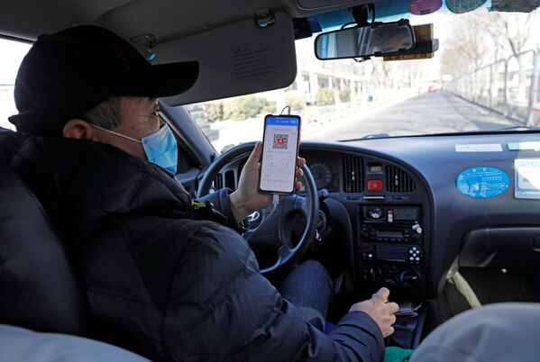 Водитель такси показывает QR-код регистрации здоровья пассажиру для сканирования перед поездкой в Пекине - Sputnik Абхазия