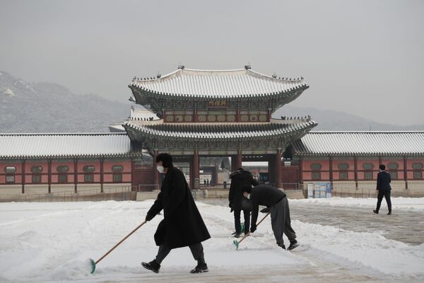 Люди в масках очищают территорию дворцового комплекса Кенбоккун в Сеуле. - Sputnik Абхазия