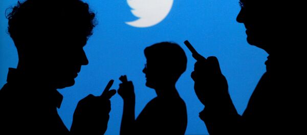 Люди в руках с мобильными телефонами вырисовываются на фоне, на котором изображен логотип Twitter, на этой фотографии, сделанной 27 сентября 2013 года - Sputnik Абхазия