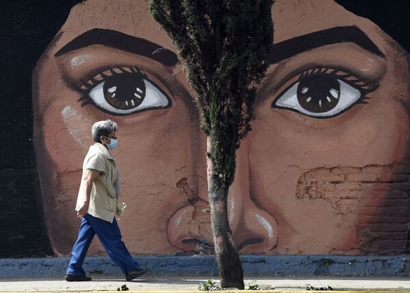 Женщина  проходит мимо граффити на одной из стен кладбища San Nicolas Tolentino в муниципалитете Истапалапа в Мехико - Sputnik Абхазия