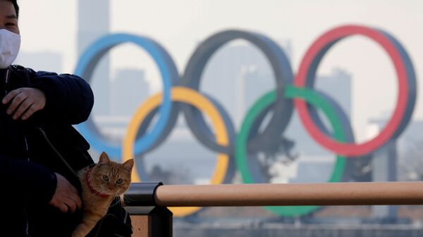 Мужчина с котом в сумке на фоне олимпийских колец в Токио - Sputnik Абхазия