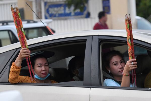 Женщины с ароматическими палочками в машине во время празднования Нового года по лунному календарю в Такмау, Камбоджа - Sputnik Абхазия