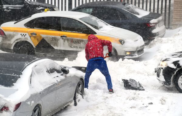 Мужчина откапывает из сугроба свою машину во дворе жилого дома в Москве - Sputnik Абхазия