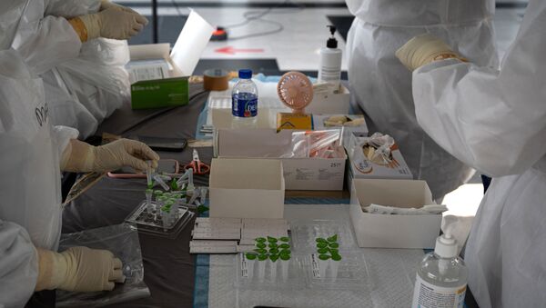 Медицинский персонал в защитных костюмах готовит наборы для тестирования на полигоне для тестирования на коронавирус Covid-19 в Шах-Аламе, на окраине Куала-Лумпура - Sputnik Аҧсны