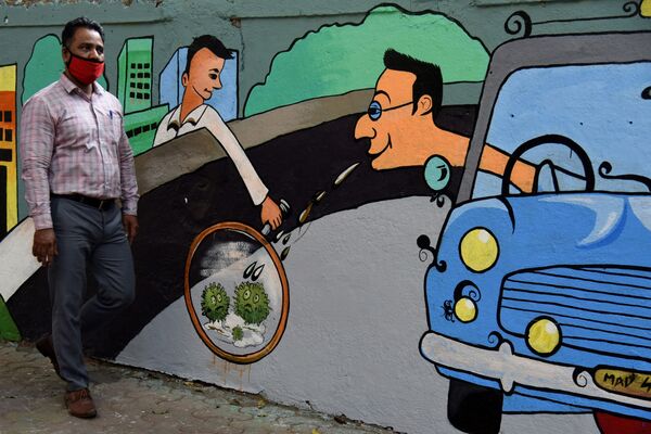 Пешеход идет мимо стены с граффити на тему коронавируса в Мумбае, Индия - Sputnik Абхазия