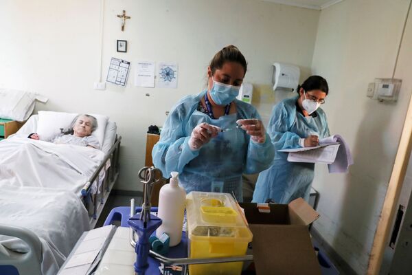 Медицинские работники в доме престарелых в Сантьяго перед вакцинацией от коронавируса пожилой пациентки - Sputnik Абхазия