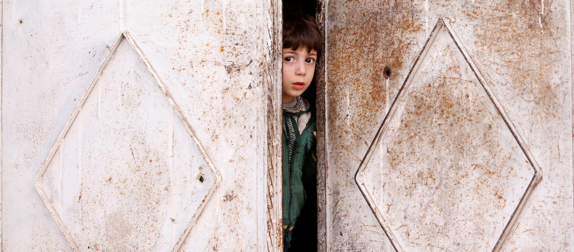Ребенок выглядывает из дверей дома в Думе, пригороде Дамаска, Сирия - Sputnik Абхазия, 1920, 14.03.2021
