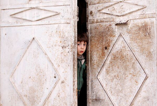 Ребенок выглядывает из дверей дома в Думе, пригороде Дамаска, Сирия - Sputnik Абхазия
