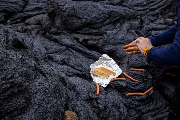 Мужчина готовит хот-доги на вулканическом участке на полуострове Рейкьянес после извержения вулкана в Исландии - Sputnik Абхазия