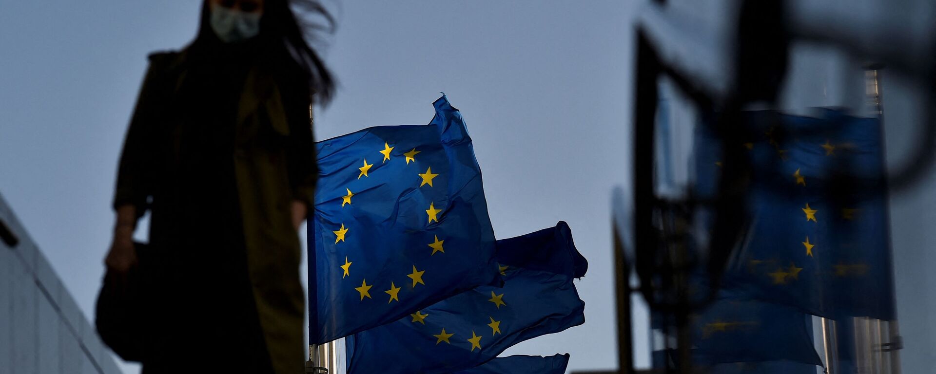 Женщина в защитной маске идет перед флагом Европейского Союза в районе штаб-квартиры ЕС в Брюсселе, 23 февраля 2021 г - Sputnik Абхазия, 1920, 27.05.2021