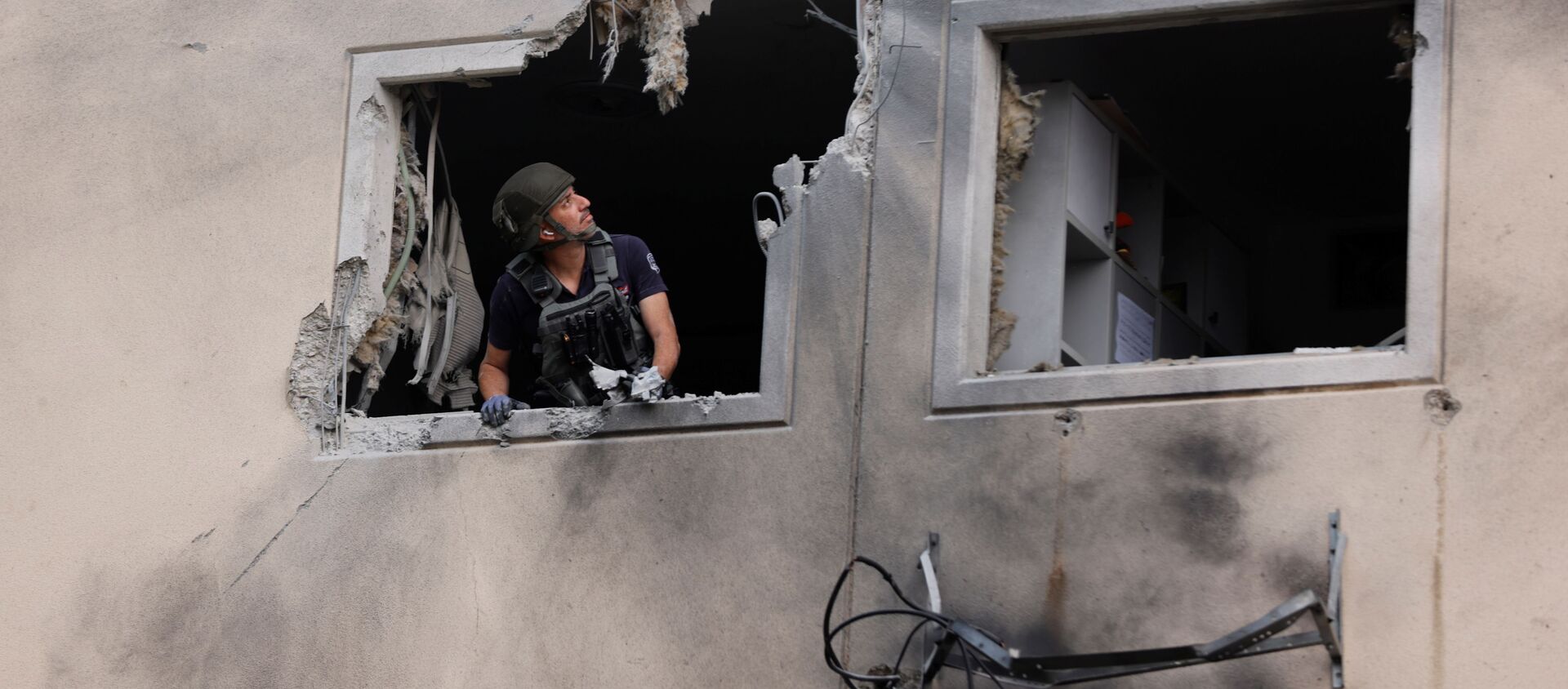 Эксперт по обезвреживанию бомб израильской полиции смотрит из окна жилого дома, который был поврежден после попадания в него ракеты, запущенной из сектора Газа, в Ашкелоне - Sputnik Абхазия, 1920, 12.05.2021