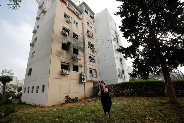 Женщина возле жилого дома, поврежденного после попадания в него ракеты, запущенной из сектора Газа, в Ашкелоне - Sputnik Абхазия
