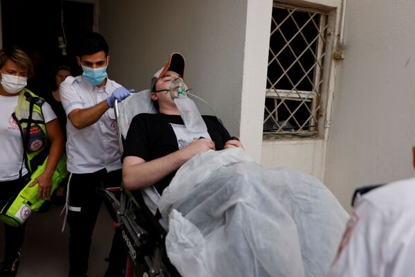 Израильские медики эвакуируют человека, получившего ранение в результате попадания ракеты из сектора Газа в жилой дом в Ашкелоне, на юге Израиля - Sputnik Абхазия