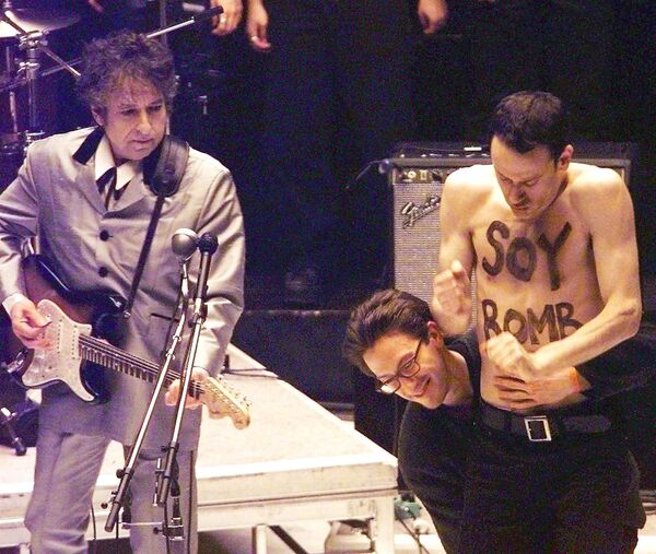 Демонстрант с надписью «Соевая бомба» уходит со сцены, когда Боб Дилан исполняет песню из своего альбома - Sputnik Абхазия