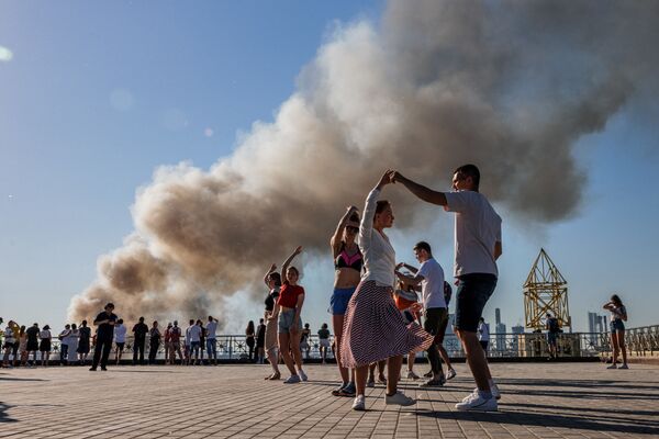 Пары танцуют самбу, пока над горящим складом пиротехники поднимается дым в Москве - Sputnik Абхазия