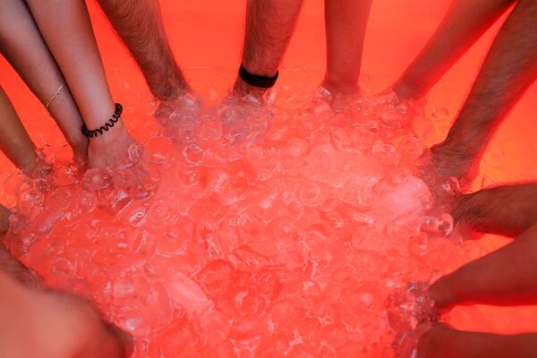 Участники ледовой терапии опускают руки в ванну со льдом в пустыне около Шарджи, ОАЭ - Sputnik Абхазия