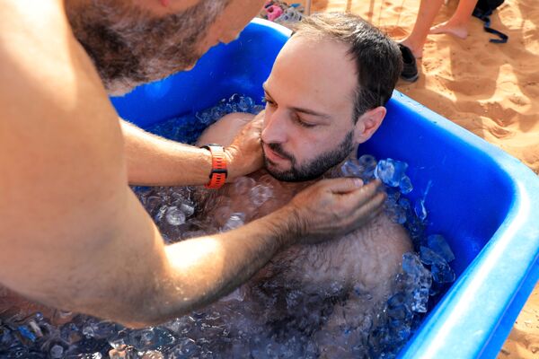 Участник ледовой терапии принимает ванну со льдом в пустыне около Шарджи, ОАЭ - Sputnik Абхазия