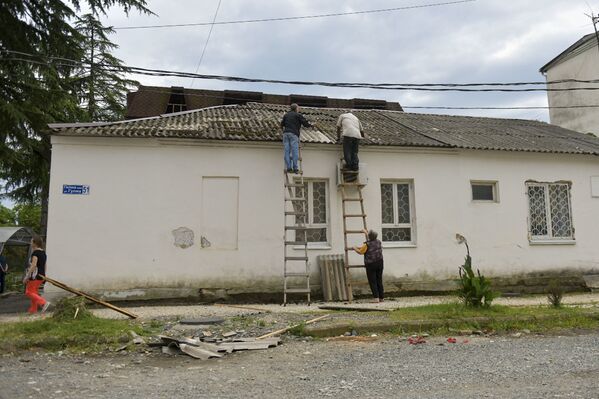 На улице Гулиа люди самостоятельно укладывают снесенный ветром шифер.  - Sputnik Абхазия