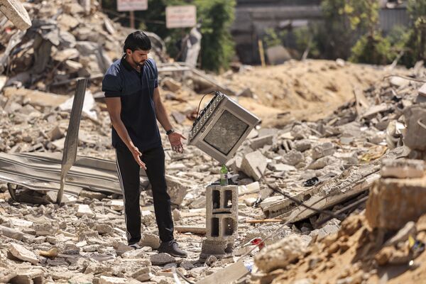 Палестинский художник-перформансист Мохаммед аль-Шенбари демонстрирует свои навыки балансирования объектов друг на друге в руинах домов, разрушенных израильскими авиаударами в Газе. - Sputnik Абхазия