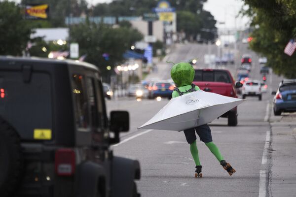 Человек в костюме инопланетянина в летающей тарелке катается на роликовых коньках по улице во время фестиваля НЛО в Розуэлле, штат Нью-Мексико, США. - Sputnik Абхазия