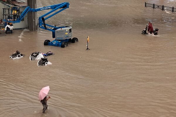 Люди идут по затопленным улицам после проливных дождей в Чжэнчжоу в центральной провинции Китая Хэнань. - Sputnik Абхазия
