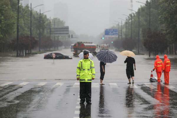 Офицер полиции на переходе затопленной улицы после проливных дождей в Чжэнчжоу в центральной провинции Китая Хэнань. - Sputnik Абхазия