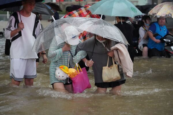 Люди идут по затопленной улице в Чжэнчжоу, провинция Хэнань, Китай. - Sputnik Абхазия