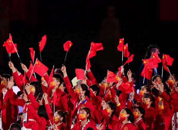 Члены китайской делегации машут флагами, входя на Олимпийский стадион во время церемонии открытия в Токио. - Sputnik Абхазия