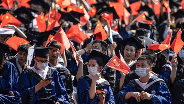 Выпускники Уханьского университета размахивают национальными флагами на церемонии выпуска в Ухане, в центральной китайской провинции Хубэй - Sputnik Абхазия