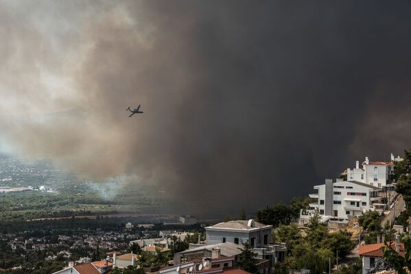 Пожарный самолет пролетает над районом Варимпомпи, где начался новый лесной пожар, в Ахарнесе, к северу от Афин. - Sputnik Абхазия