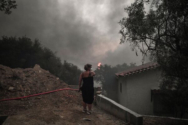 Местная жительница в маске в ​​лесу Татой недалеко от Ахарнеса, где вспыхнул лесной пожар. - Sputnik Абхазия
