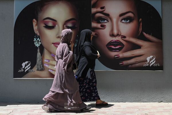 Женщины в парандже проходят мимо рекламного щита на стене салона красоты в Кабуле. - Sputnik Абхазия