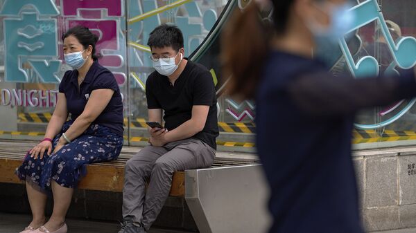 Люди, носящие маски для лица, чтобы помочь обуздать распространение коронавируса, отдыхают на скамейке возле торгового центра в Пекине в понедельник, 24 мая 2021 г. - Sputnik Абхазия