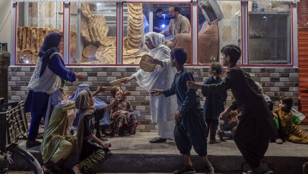 Женщина раздает хлеб нуждающимся детям перед пекарней в Кабуле - Sputnik Абхазия