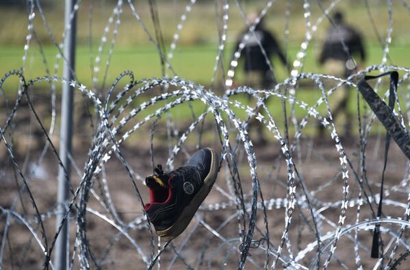 Беженцы из Афганистана сушат вещи и обувь на проволочном заграждении в лагере нелегальных мигрантов из Афганистана на белорусско-польской границе. - Sputnik Абхазия